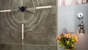 A wall with a geometric light fixture, a vase with flowers, and a book with Hebrew text. - Hotel Kazimierz III (Kraków)