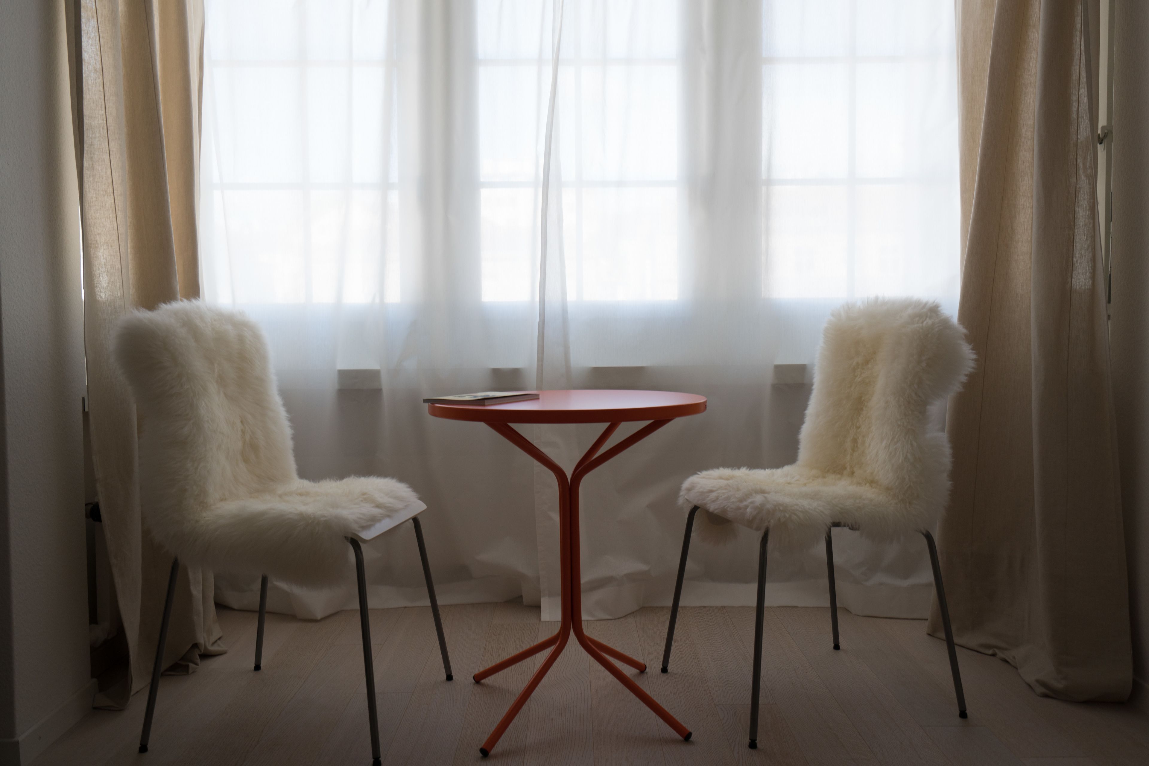 Una habitación con una mesa redonda y dos sillas de tapicería mullida.