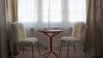 Una habitación con una mesa redonda y dos sillas de tapicería mullida.