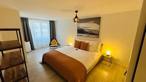 Ein Hotelzimmer mit einem großen Bett, einem Sessel, einem kleinen Tisch und einem Bild an der Wand.