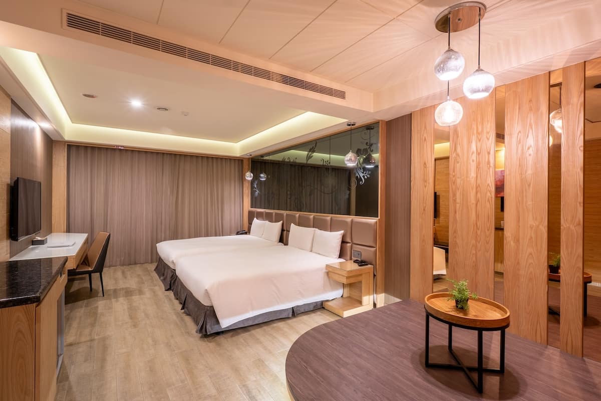 A modern hotel room with a large bed, a desk, and a seating area.