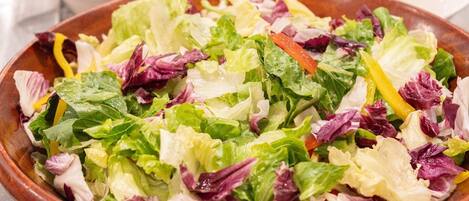 Un tazón de ensalada verde y roja con una variedad de verduras.