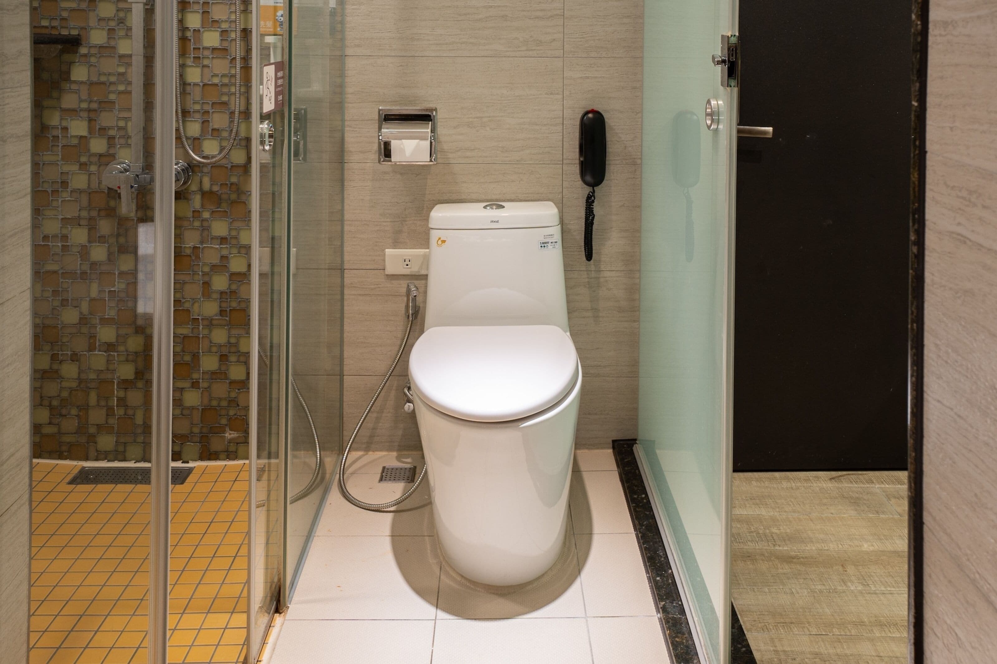 Un baño moderno con cabina de ducha de vidrio, inodoro y teléfono.