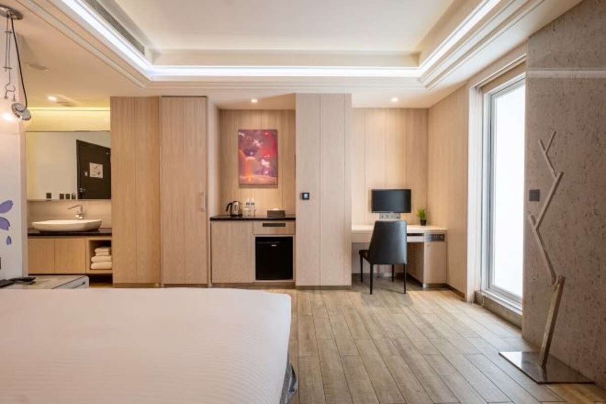 A modern hotel room with a large bed, a separate bathroom, a desk with a chair, and a TV.