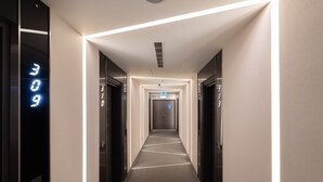 A modern hotel hallway with a central light strip, elevator doors, and a clean, minimalist design. - Guide Hotel Taichung ZiYou (Taichung)