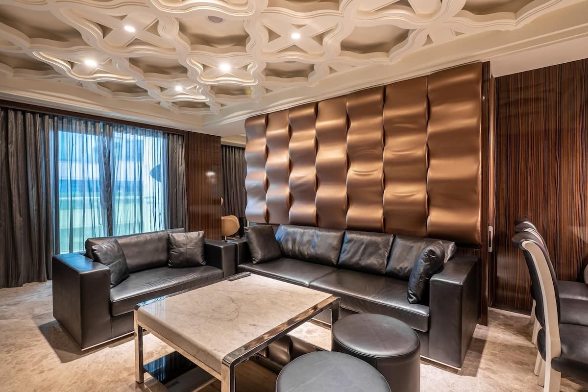 A modern living room with a sectional sofa, a glass coffee table, and a leather armchair.