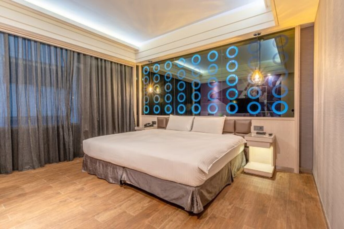 A modern bedroom with a large bed, a nightstand, and a wall-mounted light fixture.