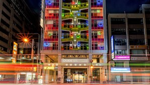 A multi-story hotel with a brightly lit facade featuring colorful neon lights and balconies. - Guide Hotel Taichung ZiYou (Taichung)