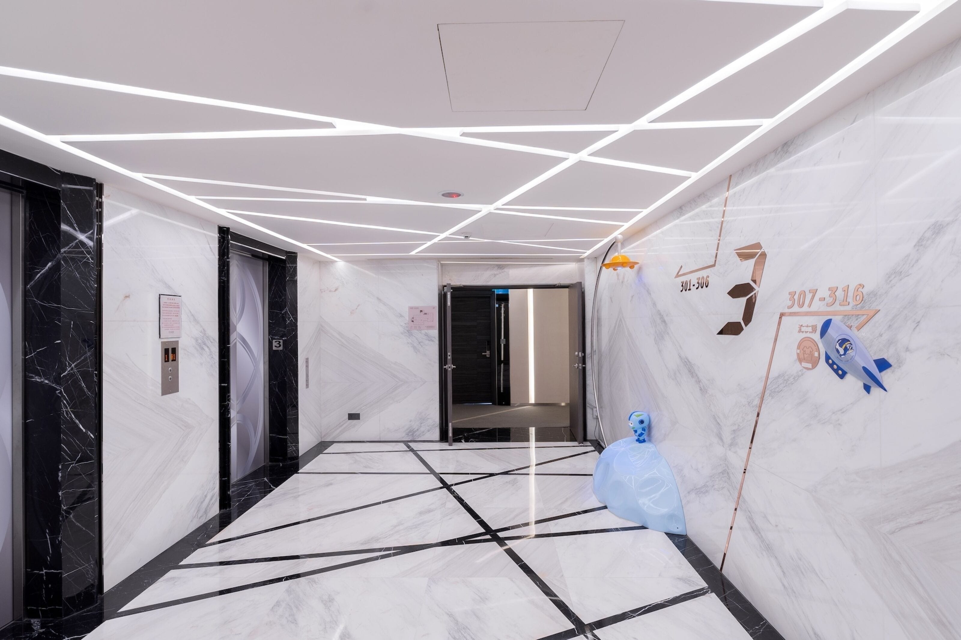 A modern hallway with marble walls and a geometric ceiling design.