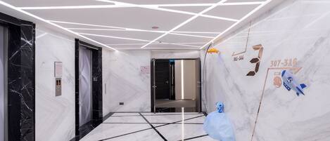 A modern hallway with marble walls and a geometric ceiling design.