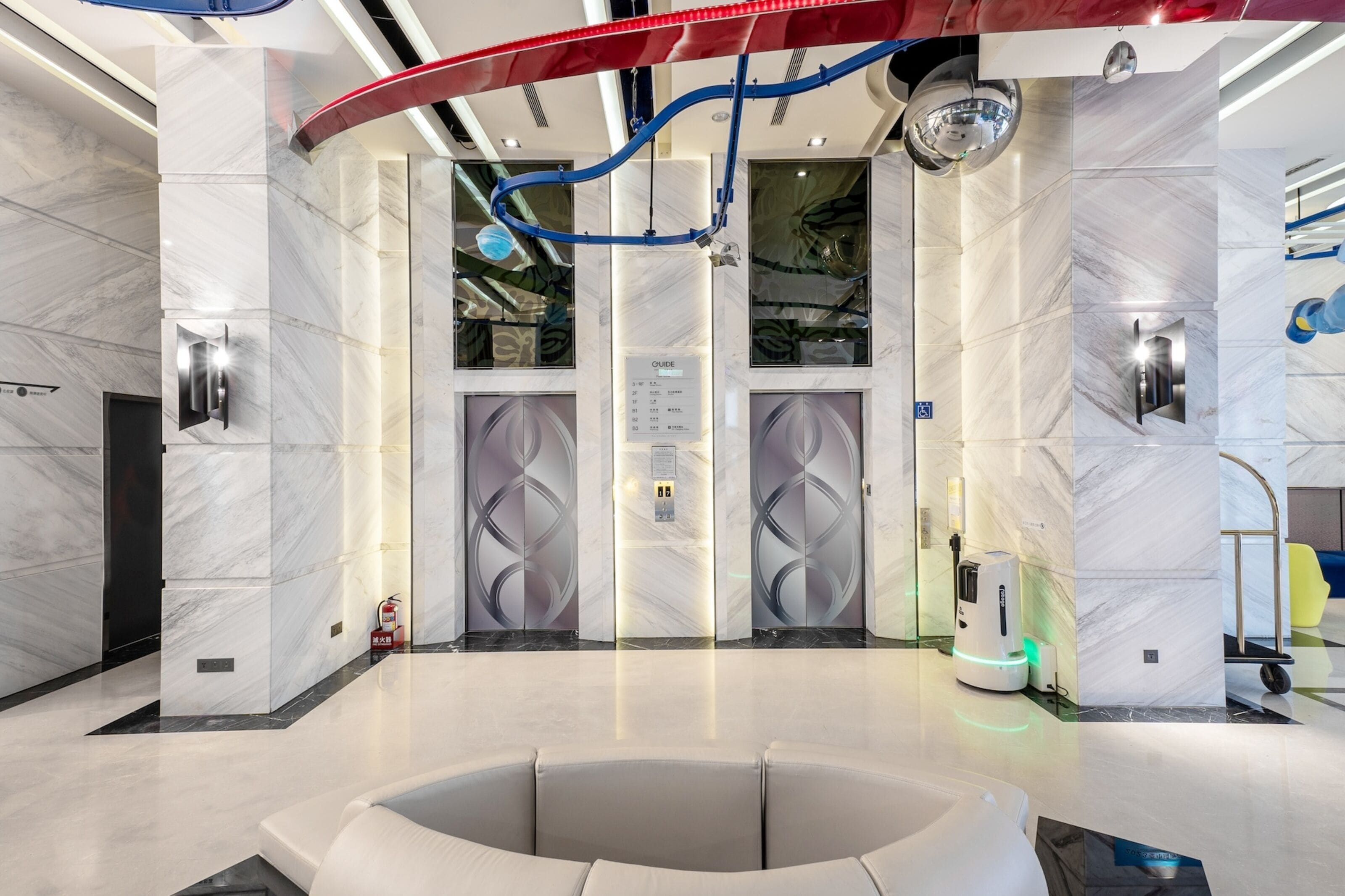 A modern elevator with a digital display, a fire extinguisher, and a robotic cleaning device.