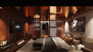 Ein modernes Schlafzimmer mit Fernseher, Kamin, einem Bett mit vielen Kissen und einem gerahmten Bild an der Wand.