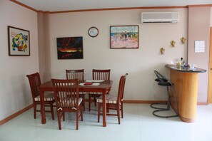 A dining area with a wooden table and chairs, a clock, and artwork on the walls.