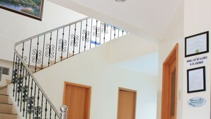 A staircase with a metal railing, a potted plant, and a wooden door in a hallway. - Dumaguete Springs Apartment (Dumaguete)