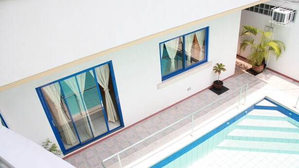 A pool area with a tiled floor, a glass railing, and potted plants. - Dumaguete Springs Apartment (Dumaguete)
