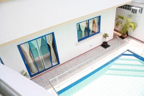 A pool area with a tiled floor, a glass railing, and potted plants. - Dumaguete Springs Apartment (Dumaguete)