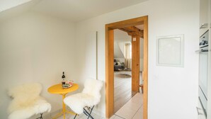 A room with a yellow table and two white chairs, a bottle on the table, and a wooden door leading to another room. - Löwenplatz Apartment near Station by Airhome (Zürich)