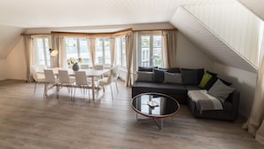 A spacious living room with a dining area, a sofa, and a coffee table. - Löwenplatz Apartment near Station by Airhome (Zürich)