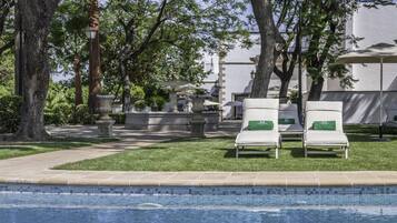 Una piscina al aire libre de temporada, sombrillas, tumbonas