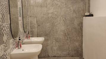 Une salle de bain avec deux lavabos, un grand miroir et un espace douche.