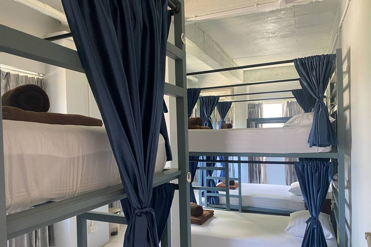 Une chambre avec des lits superposés, des rideaux attachés aux coins, un grand chiffre « 4 » visible sur le mur et une fenêtre également dotée de rideaux.