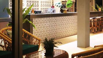 A reception area with a patterned wall, wicker furniture, and potted plants.