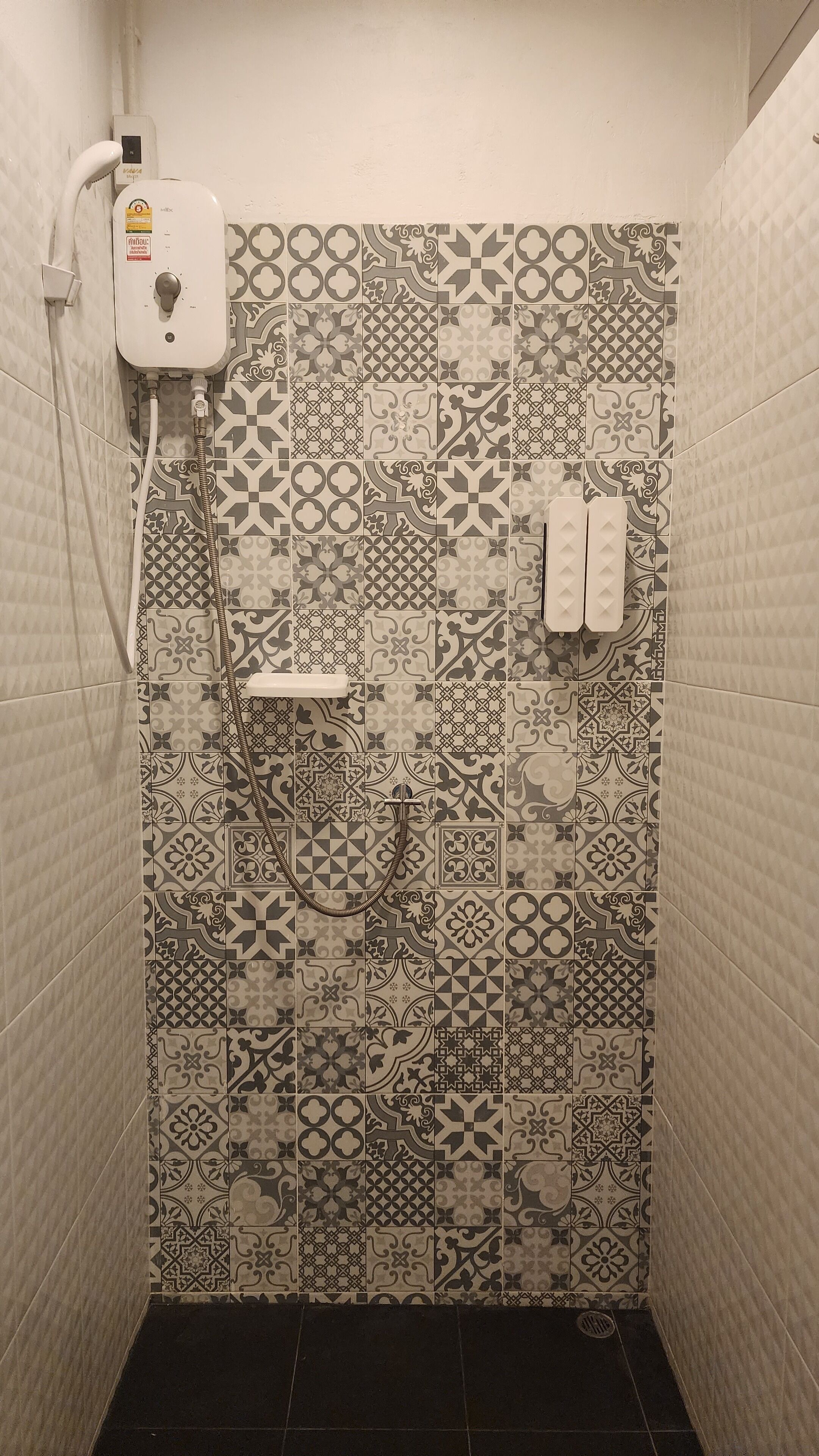 Kylpyhuone, jossa on kuvioituja laattoja, suihku ja wc.