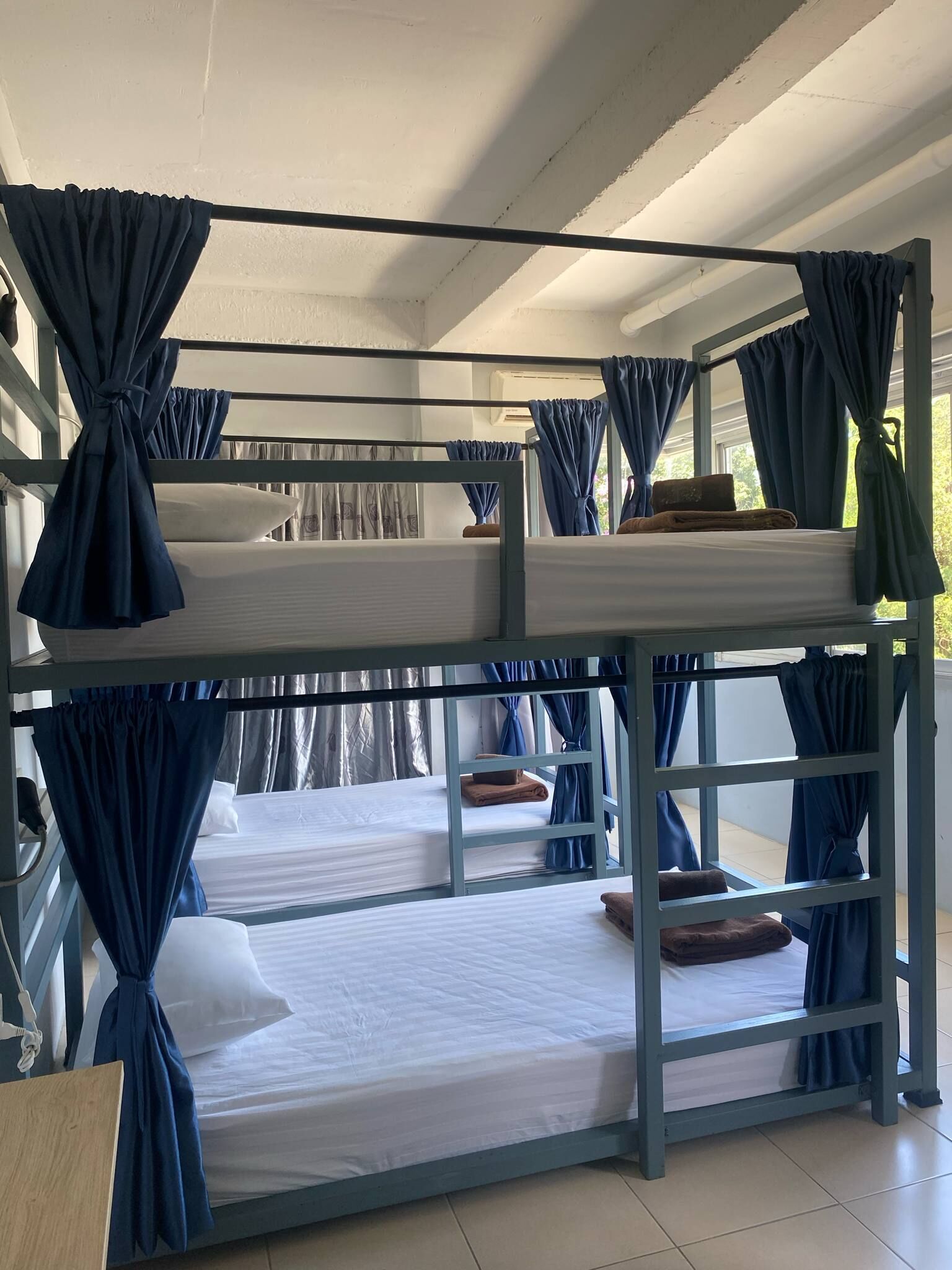 Dormitorio con literas, cortinas azules, ropa de cama blanca y una mesa de madera.