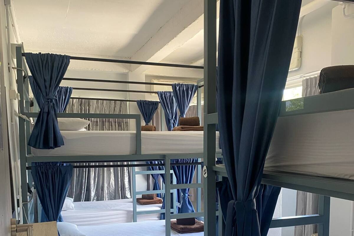 Une chambre de type dortoir, avec des lits superposés, un petit bureau et une chaise.