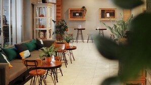 Un área de estar moderna con un sofá, sillas, mesas y plantas en macetas.