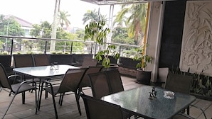 Un espace extérieur aménagé en terrasse, avec des tables et des chaises, un mur décoratif et des plantes en pot.