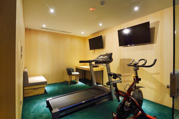 A room with a treadmill, a stationary bike, a desk, and a TV mounted on the wall. - Hotelday Plus Hualien (Hualien City)