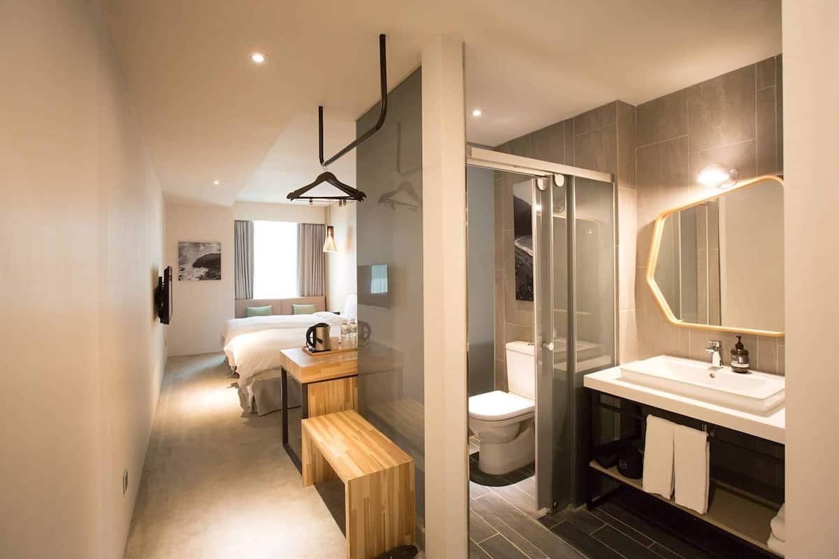 A modern bathroom with a glass shower enclosure, a white sink, and a bench.