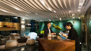 Una moderna zona de recepción con un mostrador de madera, diversas opciones de asientos y un diseño de techo único.