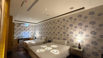 A hotel room with two beds, a desk, and a small kitchenette.
