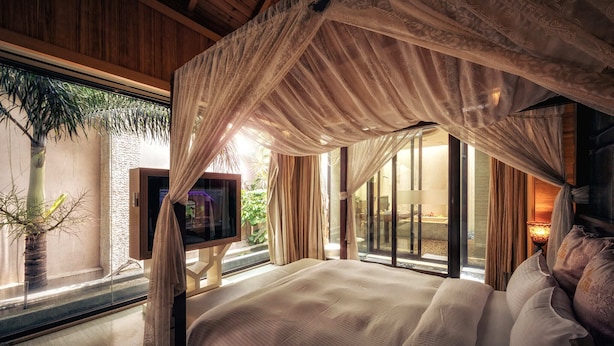 Quarto com cama de dossel, janelas amplas e vista para o exterior.
