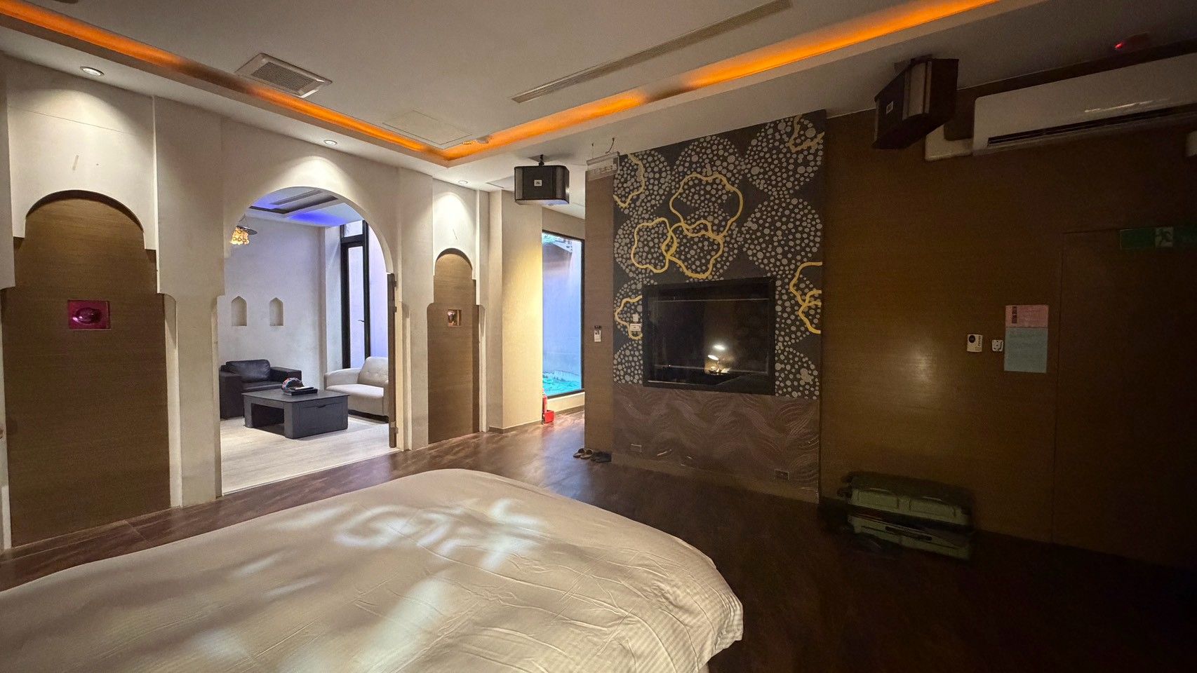 Habitación de hotel con una cama grande, un televisor montado en la pared y una zona de estar con sofá y mesa de centro.