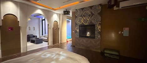 A hotel room with a large bed, a TV mounted on the wall, and a seating area with a sofa and coffee table.