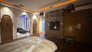A hotel room with a large bed, a TV mounted on the wall, and a seating area with a sofa and coffee table.