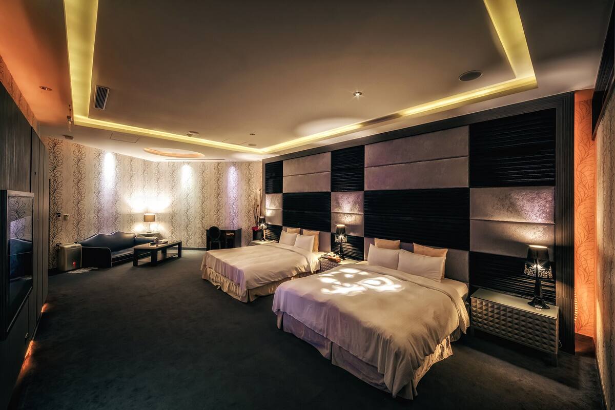 Une chambre d’hôtel avec deux lits, un canapé, un bureau et une lampe.