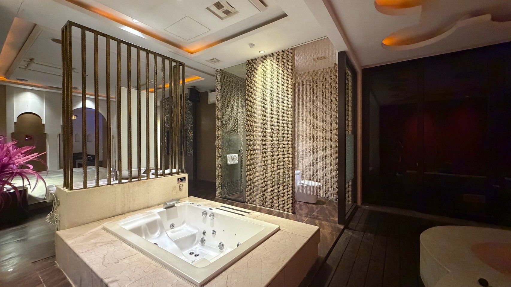 A modern bathroom with a large bathtub, a glass shower enclosure, and a decorative wall panel.