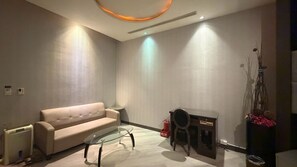 A modern living room with a sofa, a glass coffee table, a fireplace, and a decorative plant.