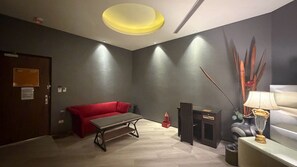 Ein Zimmer mit einem roten Sofa, einem kleinen Tisch, einer Lampe und einer dekorativen Vase.