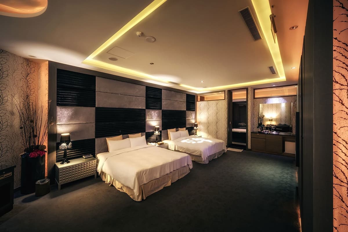 Une chambre d’hôtel avec deux lits, une coiffeuse avec un miroir et un petit coin salon.
