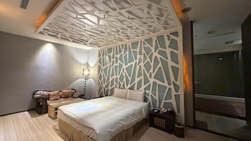 Un dormitorio moderno con cama, sofá, mesita de noche y un panel decorativo en la pared.