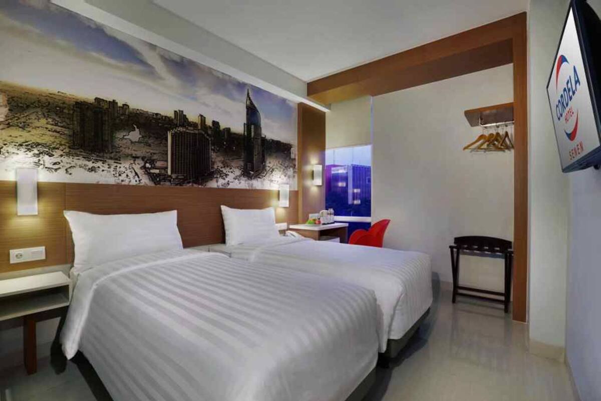 A hotel room with a large bed, a desk, a chair, and a TV.