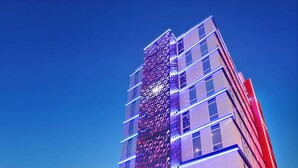 Un hôtel moderne doté d’une entrée imposante, d’une enseigne et d’une façade bien éclairée.