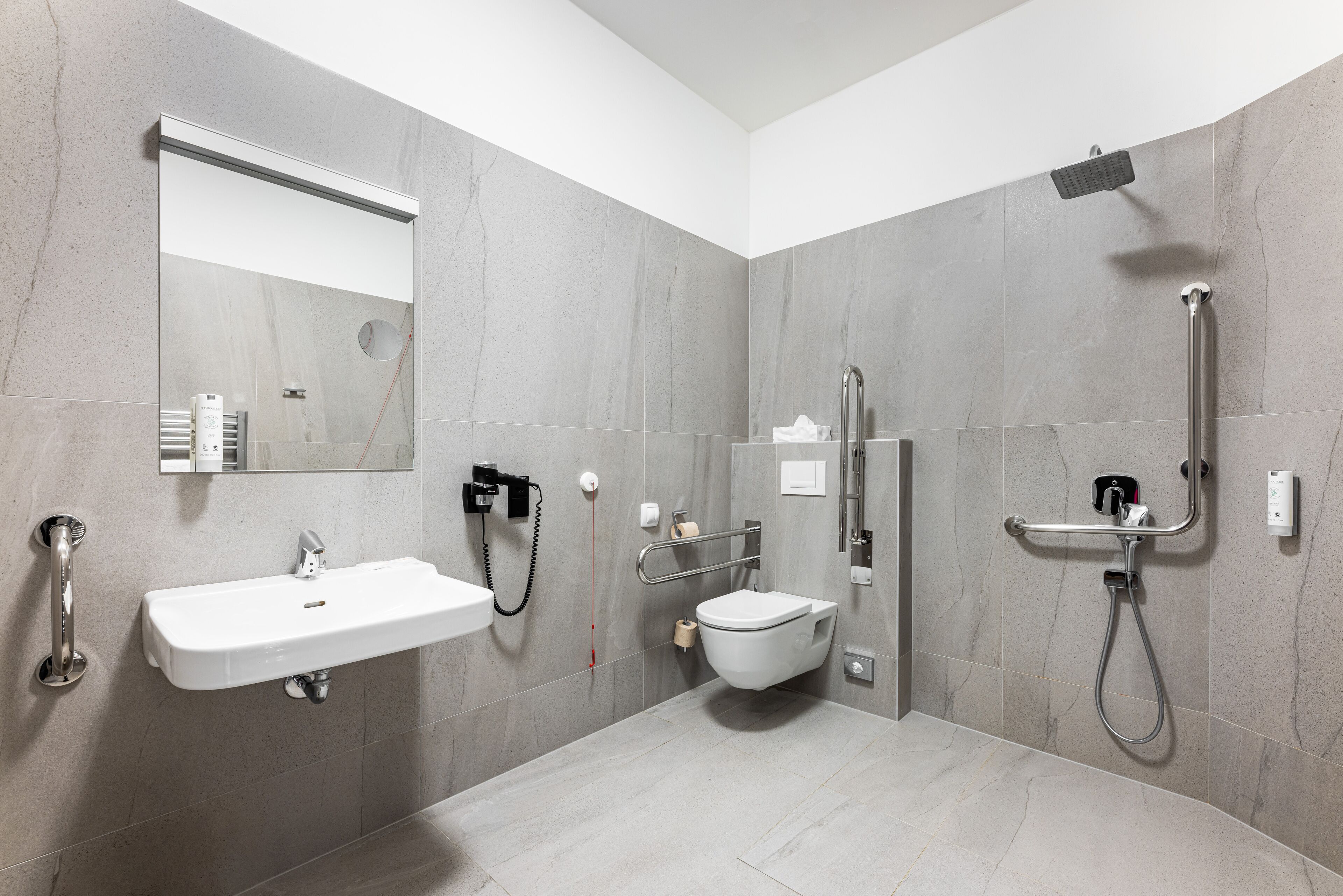 Une salle de bain moderne équipée d’un lavabo, de toilettes et d’une douche.