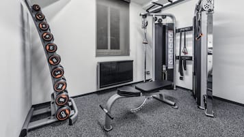A gym with a bench, dumbbells, and a squat rack.
