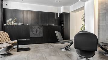 A modern reception area with a dark wood reception desk, a black office chair, and a cushioned chair.